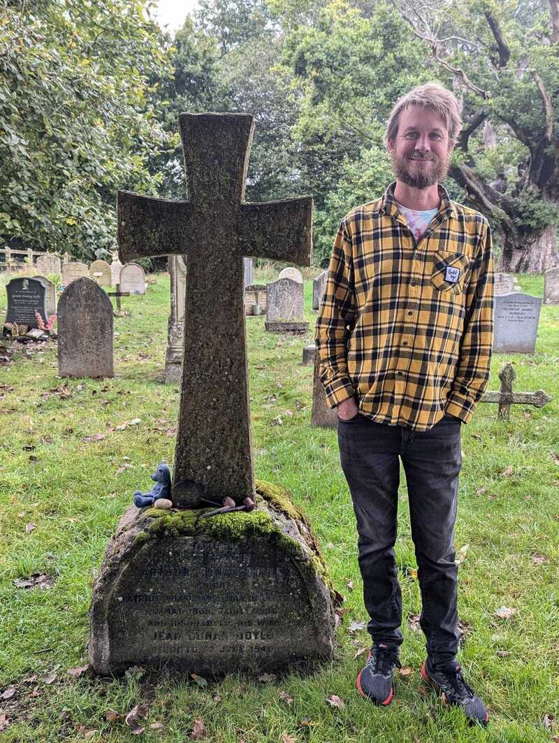 Stu standing next to a fancy headstone